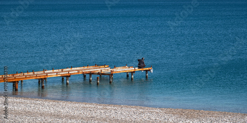 Fishermen fishing on an old, rusty pier by the sea.