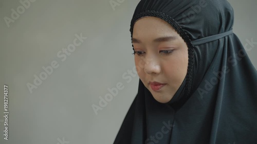 Close-up of a Muslim woman in hijab reading Quran with focus and devotion, highlighting spiritual learning and concentration.
