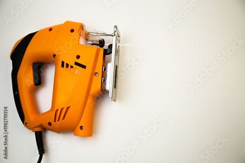 Close-up view from above of an orange jigsaw with a serrated blade on a white background with space for text. The concept of repair, laminate cutting, construction work. High quality photo
