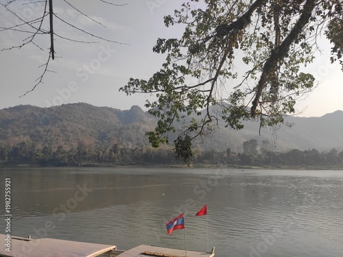 Traditional River Boat with Lao Flag and Mountain Landscape