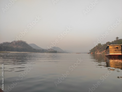 Traditional River Boat with Lao Flag and Mountain Landscape