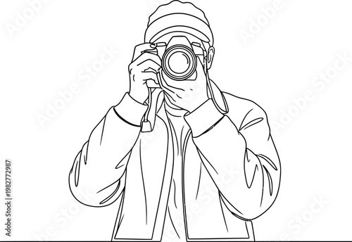 Photographer wearing a baseball cap holding a camera and taking a picture while focusing on the subject in front now