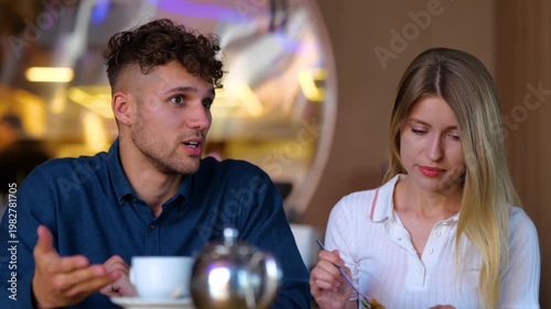 Upset woman and man talking in cafe about problem in relationships. Couple sitting at table in cafe together. Relationship problem concept. Real time
