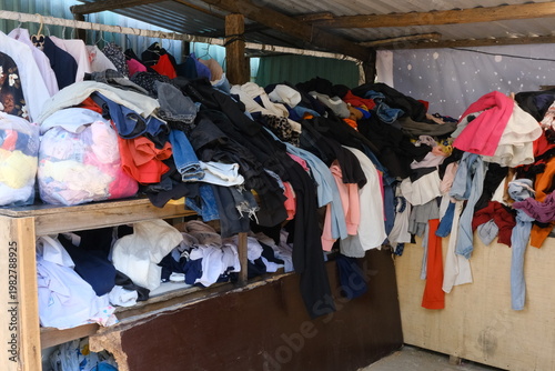 Konstfotografi A cluttered display of assorted clothing piled on wooden shelves in a market setting
