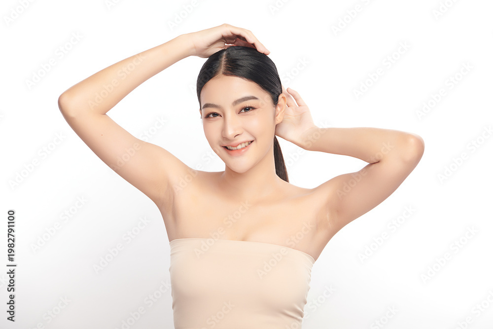 Obraz premium Beautiful Young Asian woman Raises her hands to Showcase clean and hygienic underarms Against a white background, Smooth armpit cleanliness and protection concept