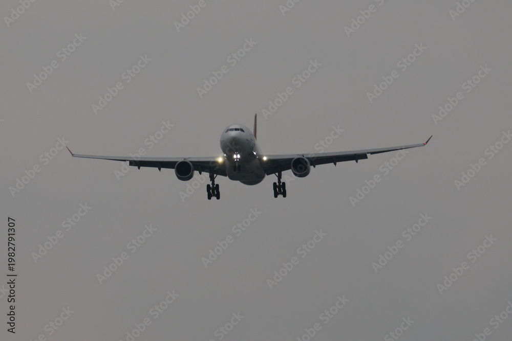 Fototapeta premium Commercial airplane landing at dusk with landing lights on.