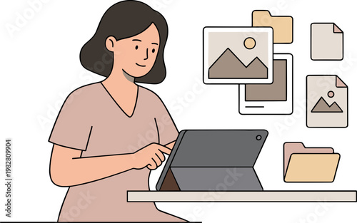 Woman sitting at a desk working on a tablet with photos and files nearby.