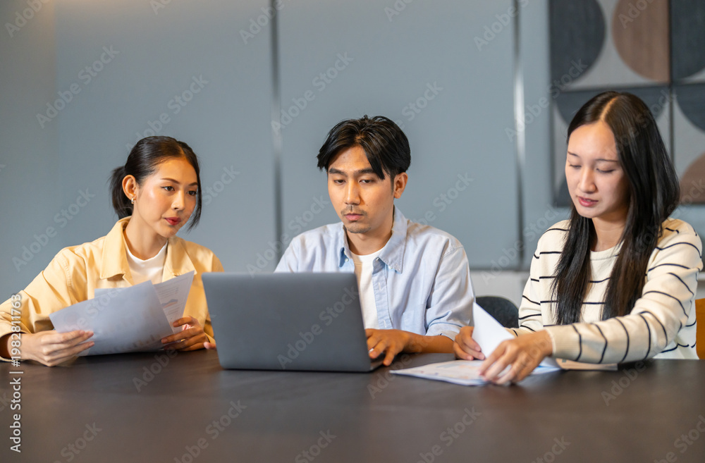 Fototapeta premium Asian digital marketing agency team analyzing SEO and ads performance on table, Young business professionals discussing campaign metrics, conversion rate and online marketing strategy concept