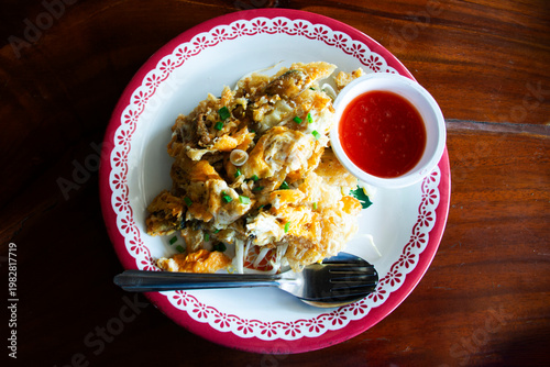 Traditional thai street food Crispy Fried Mussel Pancake or Fried Oyster with Egg cuisine meal stir fried with egg and vegetable mix spices sauce at local restaurant cafe shop in Bangkok, Thailand