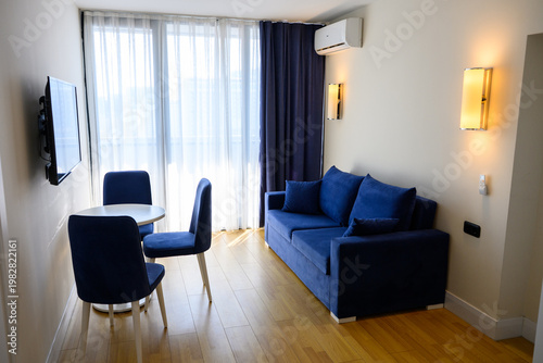 Modern studio apartment interior with blue sofa and dining area, contemporary hotel room design. Rental property real estate concept, apartment hotel, hospitality design and home comfort