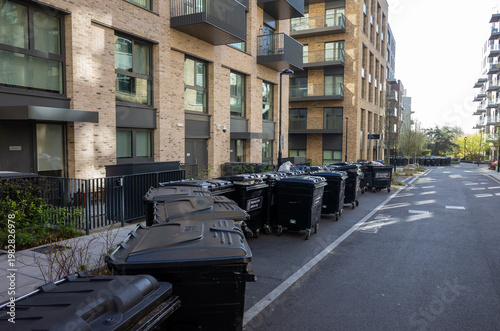 Row of black garbage bins along urban apartment street