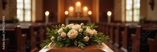 Funeral flowers arrangement on casket in peaceful church interior, candles provide soft lighting creating a somber but respectful atmosphere.
