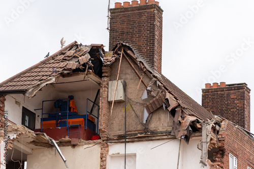 Partially demolished brick house with damaged roof