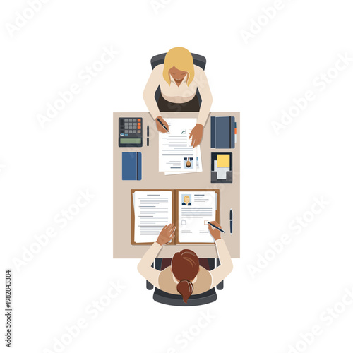 Two businesswomen working together on papers at a desk from above