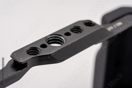 Close-up of black mechanical component with threaded holes