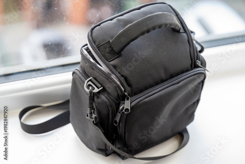 Compact black camera bag on windowsill