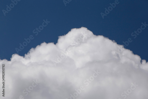 top of white mountain-like fluffy cloud in a blue sky