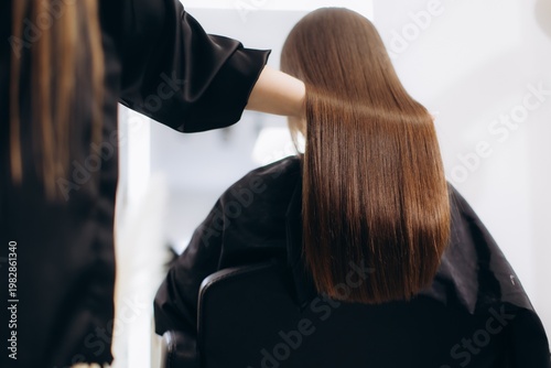 Fotografie Professional hairstylist doing keratin treatment on woman's hair