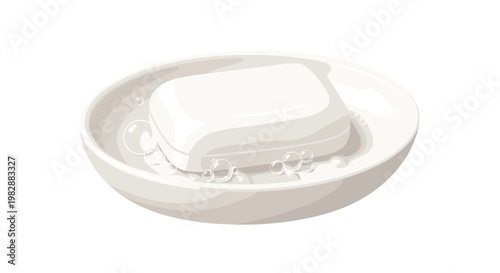 A pristine bar of white soap sits inside a matching ceramic soap dish surrounded by delicate translucent bubbles against a bright white background surface.