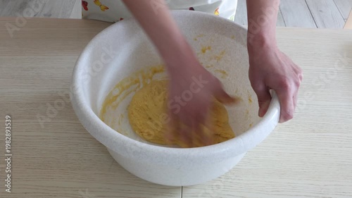 Woman hands kneading fresh dough in a white bowl