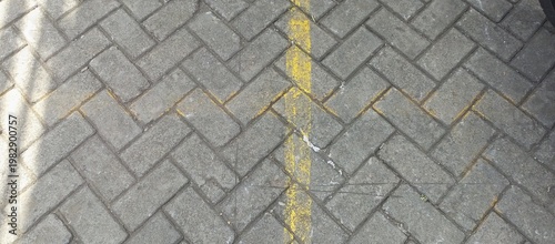 Fotografi Gray paving blocks with yellow line marking