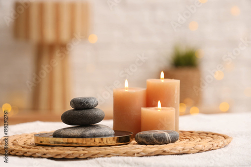 Photography Spa stones with burning candles on couch in salon, closeup