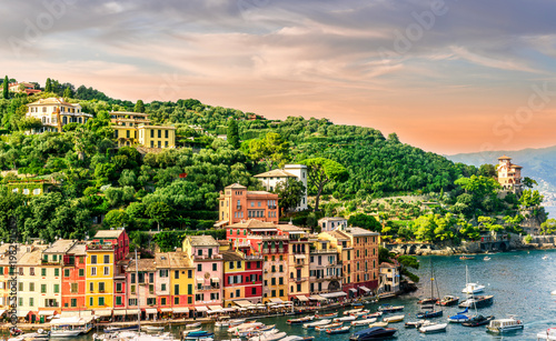 beautiful landscape of famous italiat resort Portofino in Luguria with ancient houses and buildings of hotels and restaulants along the embarkment of a sea gulf with sunset golden light