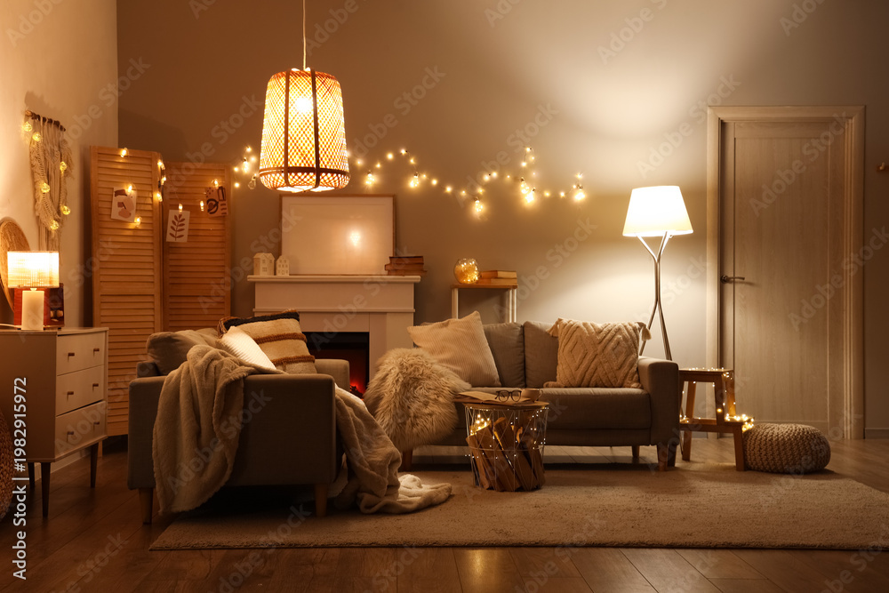 Obraz premium Interior of living room with sofas, fireplace and glowing lights at night
