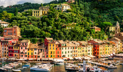 sunset seascape in a beautiful summer bay of Portofino with blue azure sea water, nice yacht boats, green mountain slopes and scenic vintage ols buildings of a town