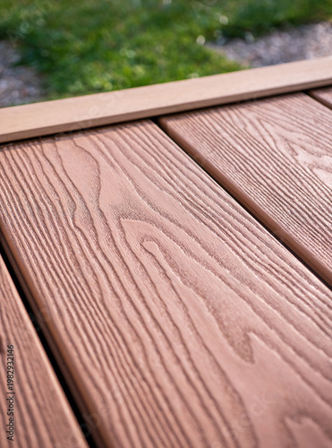 Принти на полотні Close-up of WPC composite decking boards with realistic wood grain texture and edge trim detail, outdoor terrace flooring with blurred garden background