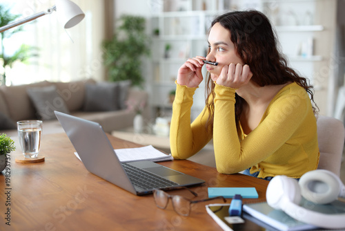 Distracted student wasting time playing with a pen at home