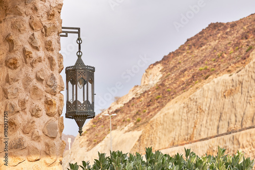 Traditional Arabic lantern fanous on ancient stone wall with mountain background