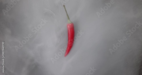 Red birds eye chilli on black stone slate background smoke vapour mist flowing rapping moving