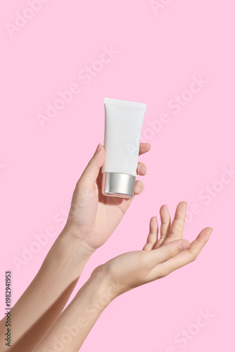 Foto Two hands gently presenting cosmetic cream jar on pastel pink background