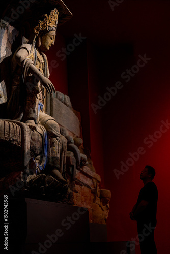 Cuadro en lienzo A devout man pays homage to a giant Buddha in a Buddhist grotto