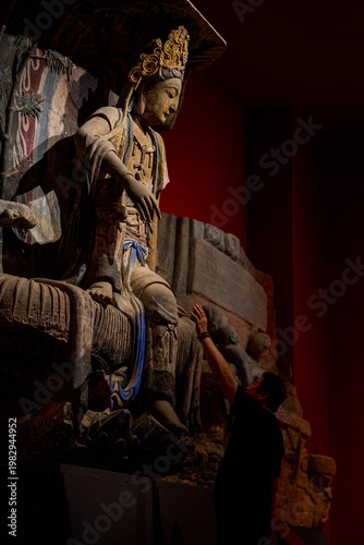 A devout man pays homage to a giant Buddha in a Buddhist grotto