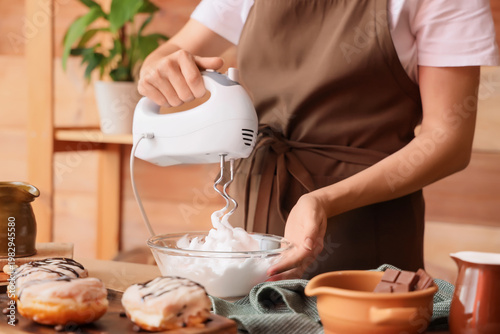 фотографія Woman whipping egg albumen with mixer in kitchen