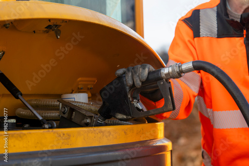 Foto Worker refills fuel tank of machinery at construction site in daylight hours