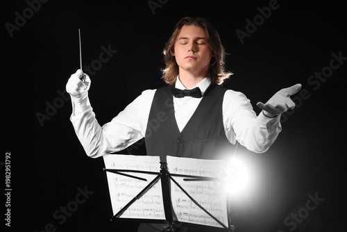 Male conductor with note sheets on dark background
