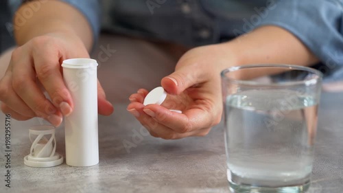 Female hands open jar of medicine and drop effervescent pill into glass water. Take pills drugs medicament vitamins