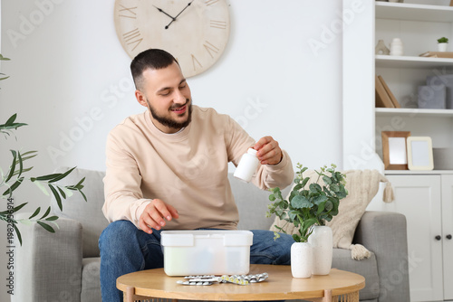 Young man taking pills from...