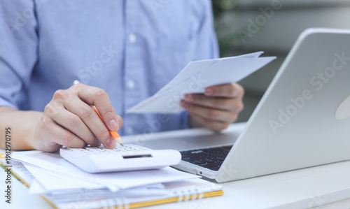 close up man hand press on calculator and check invoice letter from bank  to check about debt and spending monthly for people lifestyle and inflation economic concept