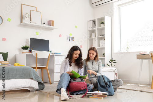 Female students with copybook studying in dorm room