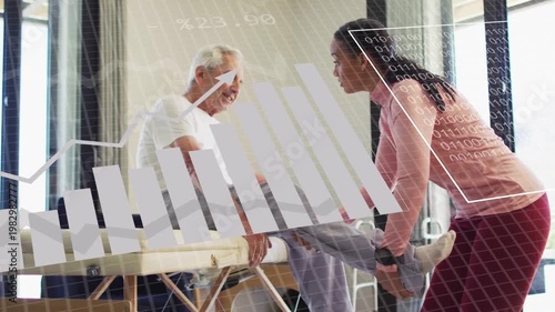 Therapist leaning holding patient leg on table, guiding ROM while rehab charts overlaying tracking