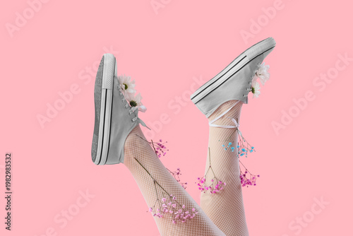 Obraz na płótnie Female legs in tights and sneakers with gypsophila flowers on pink background