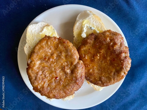 Two patties on freshly buttered rolls look like two giant eyes staring from the plate