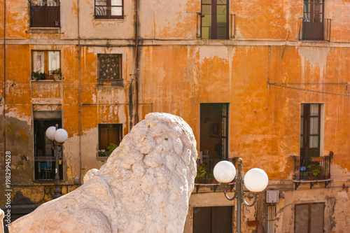Ancient lion sculpture against the aged townhouse, Piazza Palazzo, Cagliari, Sardinia, Italy