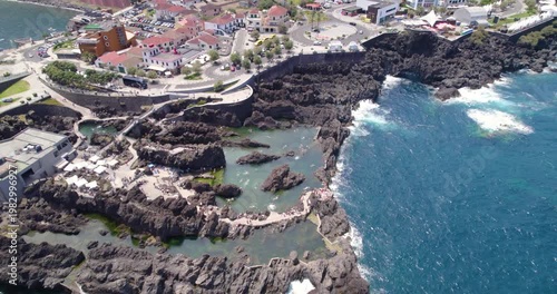 Drone sweep over the dark volcanic rocks and crashing waves of Porto Moniz.