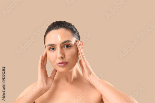 Beautiful young woman with dripping honey on her face against beige backgroun...