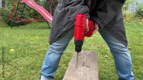 close view of cordless screwdriver tightening screw into wooden surface forward rotation diy repair assembly process power tool in action workshop detail